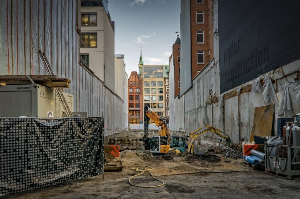 Construction site in an urban area with excavators and scaffolding, showcasing development.